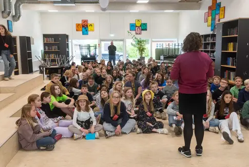 Skolebørn sidder på gulvet og lytter