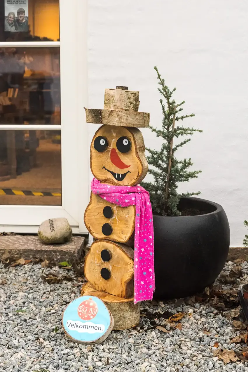 Snemand fremstillet i træ, iført pink halstørklæde