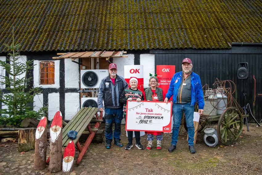 Fire personer står med en OK gavecheck
