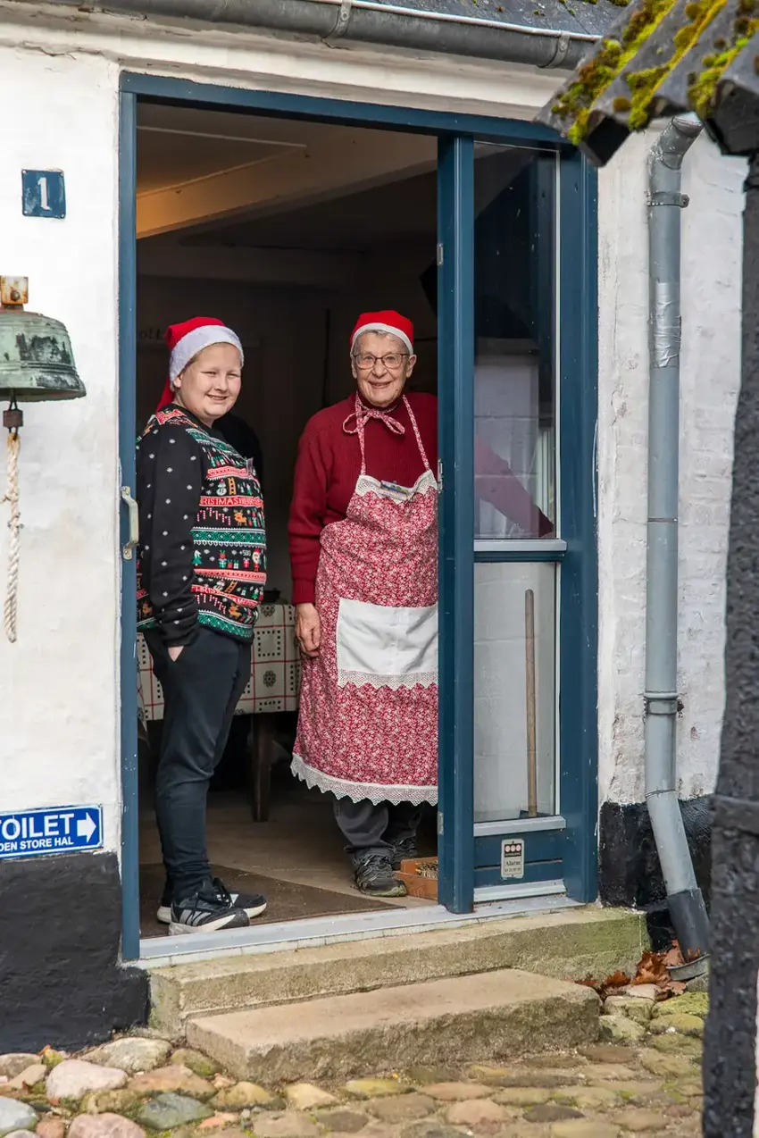 To ældre kvinder står i døråbningen og smiler