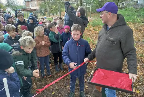Mand med grøn jakke og hat står sammen med mange børn