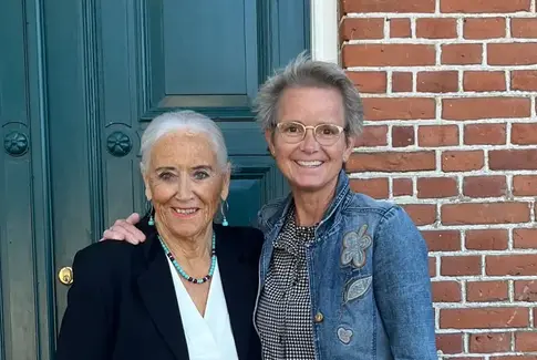 To kvinder står foran en dør og smiler