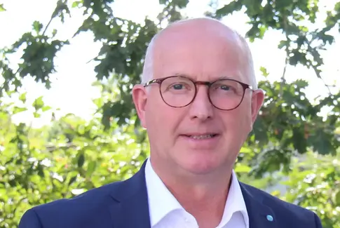 Mand med briller iført blå jakke og hvid skjorte